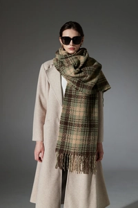 Close-up of moss green and brown plaid scarf featuring long tassels and soft knit texture