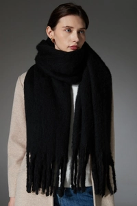 Close-up of black chunky knit scarf with long tassels showing soft mohair texture
