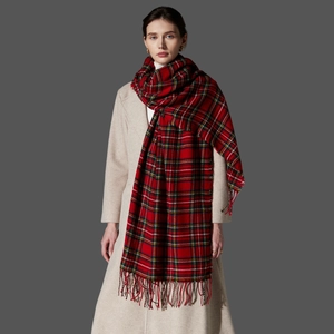 Detail of red tartan scarf with fringe tassels worn over a classic beige wool coat