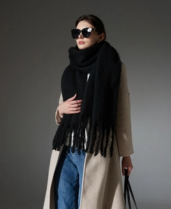 Close-up of thick winter black mohair scarf with fringe detail and soft wool texture