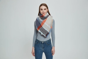 Détail d'une écharpe à carreaux épaisse avec pompons et motifs orange et bleu