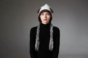 Detail of knit cat ear hat with black and white faux fur tassels on a model