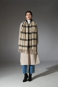Détail d'une tenue d'hiver avec écharpe à carreaux kaki et long manteau en laine avoine