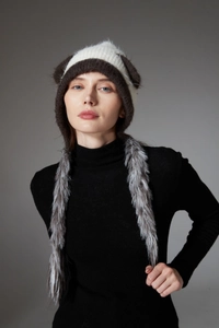 Close-up of knit winter hat with cat ears and grey faux fur earmuffs on a model