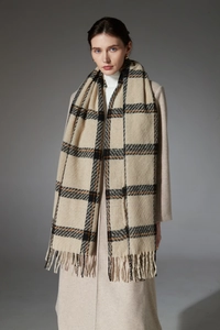 Détail d'une écharpe à carreaux beige avec des pompons doux et une finition à franges