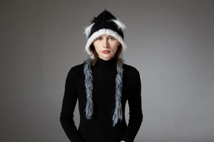Detail showing the fluffy cat ears and black-white knitted textures on a winter earflap hat
