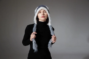 Detail of grey and white knit trapper hat with cat ears and long faux fur tassels