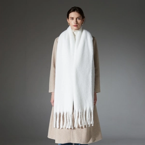 Chunky white loop yarn scarf with thick fringes on a model in a beige coat