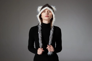 Close-up of knit winter hat with cat ears and long faux fur tassels on model