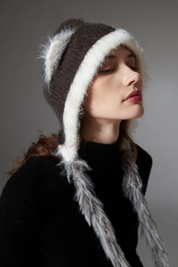 Close-up of winter knit hat with white faux fur lining and plush ear flaps with tassels