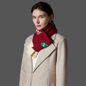 Red knit Christmas scarf with white snowflakes and green dots worn with beige coat