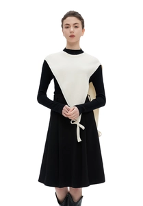 Detail of a white triangular knitted shawl accessory over a classic black knit top