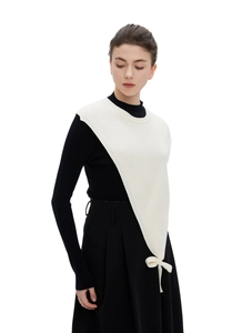 Detail of cream asymmetrical knit shawl with bow tie over a black sweater