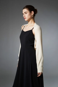 Detail of elegant beige knit shrug paired with a minimalist black sleeveless maxi dress