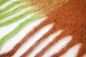 Close-up of thick winter scarf with long tassels and green to brown gradient faux mohair fabric