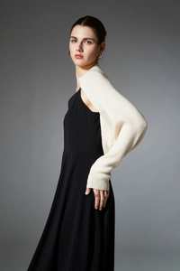 Close-up of knit texture on cream shawl shrug paired with black sleeveless dress