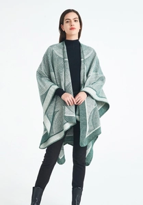 Détail du poncho en laine tricotée surdimensionné avec motif géométrique vert et blanc
