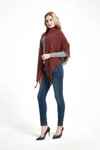 Detail view of reddish-brown chunky knit poncho with long fringe trim on a female model