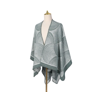 Détail d'un châle en laine vert et beige montrant des motifs géométriques et maille