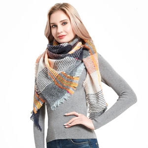 Detail of multi-color plaid knit scarf with fringed edges in orange and navy blue