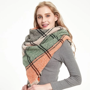 Close-up of thick knitted plaid scarf with fringe edge in orange and green tones