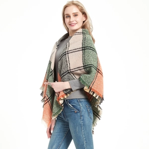 Detail of plaid poncho shawl featuring classic green and orange checks with fringed edges