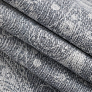 Macro shot of blue-grey paisley jacquard fabric showing intricate floral weave texture