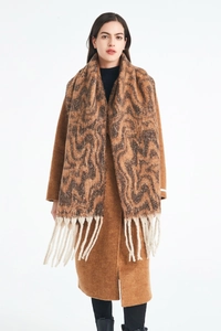 Close-up of wavy jacquard pattern and long ivory tassels on an earth-tone scarf