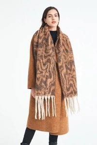 Close-up of brown wavy knit pattern and long white tassels on a winter scarf