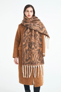 Detail of a thick winter scarf with brown wave pattern and long tassels on wool coat