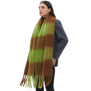 Thick winter plaid scarf in green and brown with long tassels on a female model