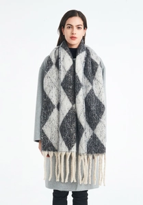 Detail view of the gray and beige argyle knit scarf with fringe tassels on model