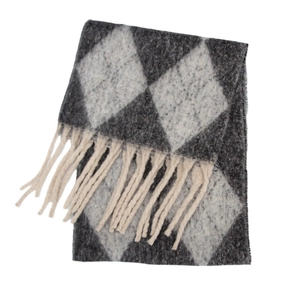 Detail view of the thick boucle knit argyle pattern and long fringe tassels on the scarf