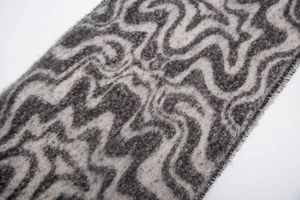 Detail view of the soft grey and beige marble wave texture on the fringe scarf
