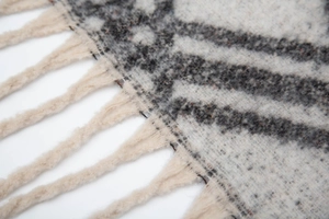 Close-up of fluffy checkered knit scarf with cream base and twisted fringe tassels
