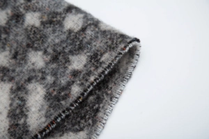Macro detail of thick leopard print scarf showing soft knit texture and stitched edges
