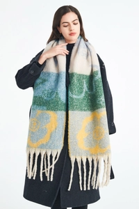 Detail of chunky knit scarf with colorful floral jacquard pattern and long tassel fringes