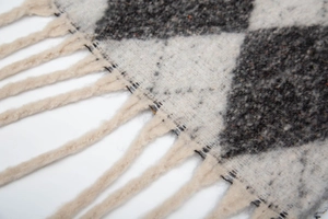 Detailed macro view of the soft knitted argyle pattern and fringe on this scarf