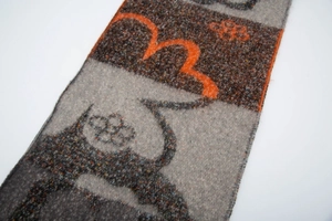 Detailed knit texture of four-leaf flower scarf with grey and orange boucle yarn