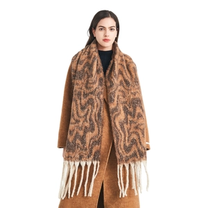 Thick knit winter scarf with wave pattern and tassels, paired with a wool coat