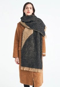 Detail of thick geometric gray and beige scarf with fringe on a brown wool coat