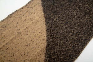 Detailed close-up of thick knitted scarf with color block pattern and fringed edges