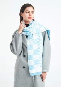 Detail of blue and white checkered knit scarf paired with a grey wool coat on model