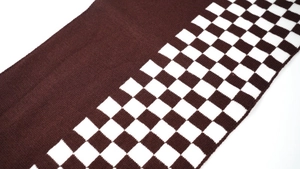Macro shot of dark brown and white checkerboard knit texture on winter scarf fabric