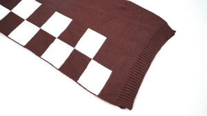 Macro shot of knit checkerboard scarf showing brown and white pattern texture and ribbed edge