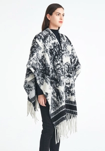 Detail of knit shawl with monochrome ink pattern and fringe trim over black turtleneck