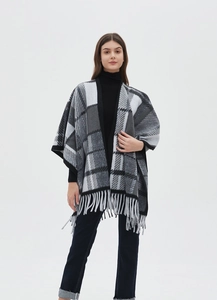 Detail of gray plaid poncho wrap with dense fringe hem and high-quality woven fabric