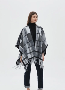 Detail of grey plaid knit shawl featuring soft texture and long fringe hemline tassels