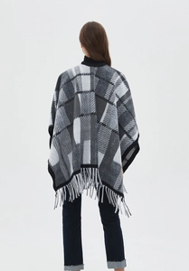Detailed view of women's long wrap shawl featuring black and white plaid and tassel hem