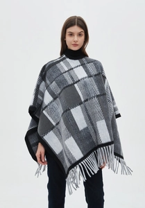Detail of grey and black plaid poncho with soft texture and delicate fringe hemline